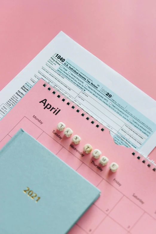 a calendar sitting on top of a pink table, by Ben Zoeller, trending on pexels, pills, photograph of april, documents, ross tan