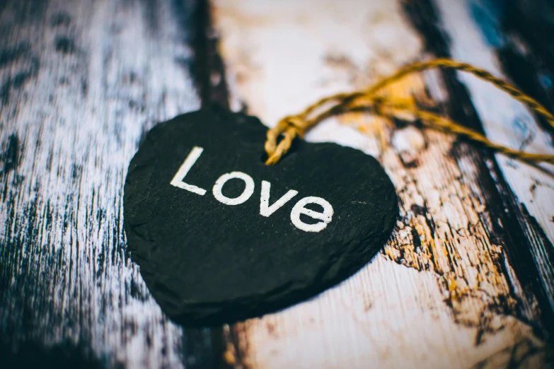 a black heart with the word love written on it, a picture, by Sylvia Wishart, unsplash, a wooden, ornament, avatar image