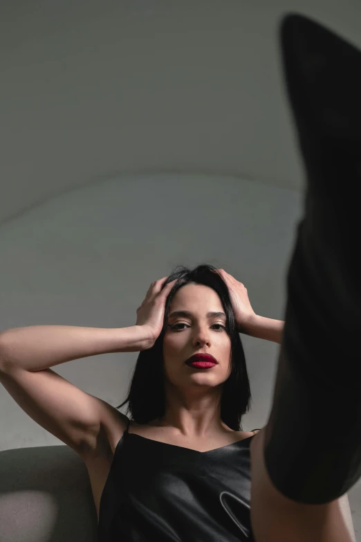 a woman sitting on a couch with her legs up, inspired by Marina Abramović, pexels contest winner, hyperrealism, hands in her hair, standing in front of a mirror, slicked black hair, lipstick