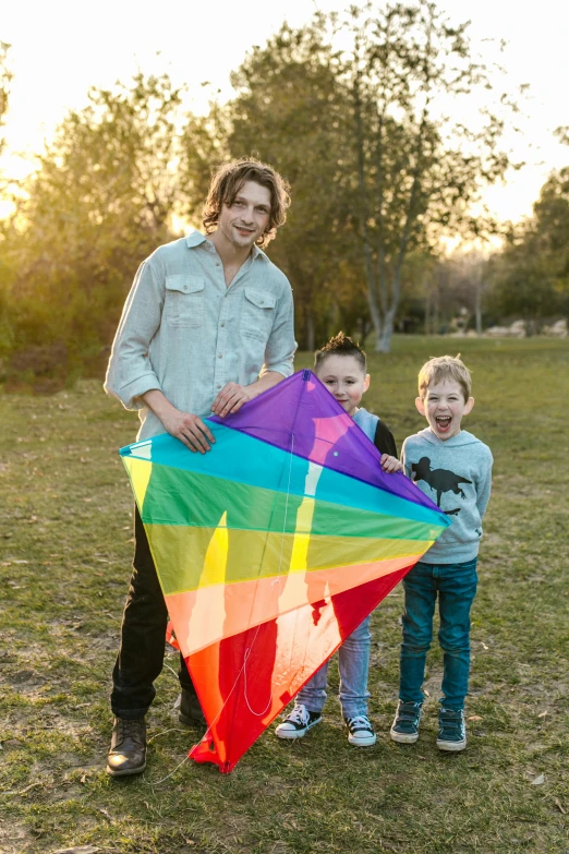 a man and two children holding a rainbow kite, lachlan bailey, multiple colors, large tall, boys