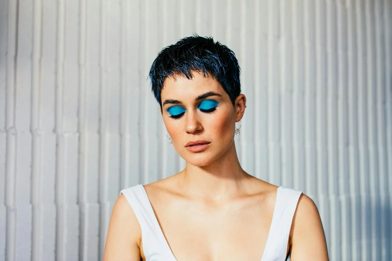 a woman with blue eyes is posing for a picture, an album cover, inspired by Elsa Bleda, trending on pexels, hurufiyya, short blue haired woman, christina kritkou, pixie cut, photoshoot for skincare brand