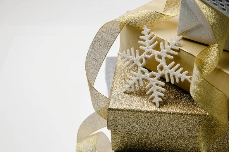 a gold gift box with a snowflake on top of it, pexels, visual art, silver，ivory, three - quarter view, ribbon, detail shot