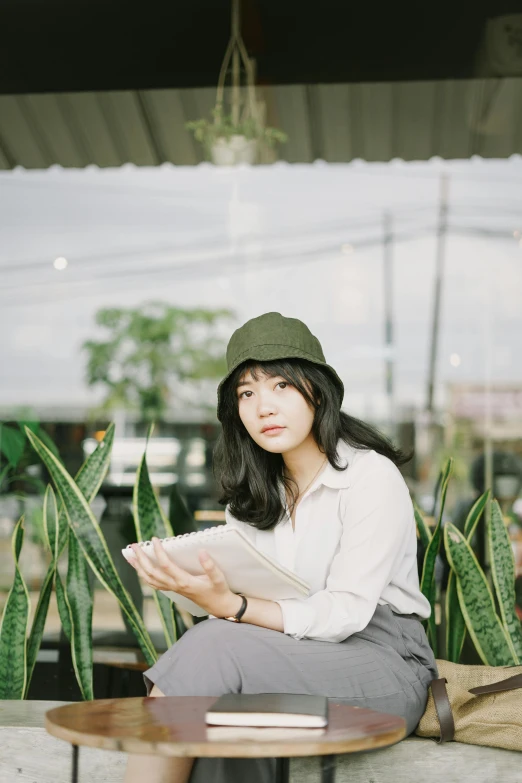 a woman sitting on a bench reading a book, by Tan Ting-pho, pexels contest winner, holding a cactus, 🤤 girl portrait, green hat, ulzzang