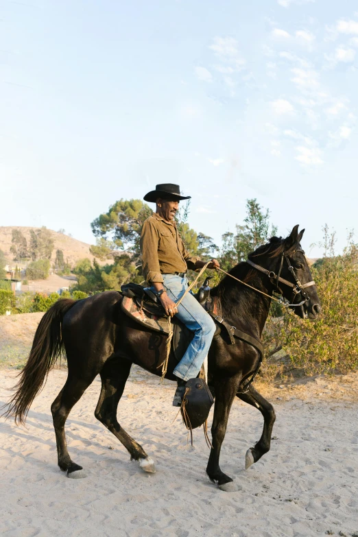 a man riding on the back of a black horse, malibu canyon, fullbody of standing tom selleck, jen atkin, color photo