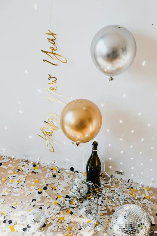 a cake sitting on top of a table covered in confetti, wine bottle, balloon, silver and gold, wall art