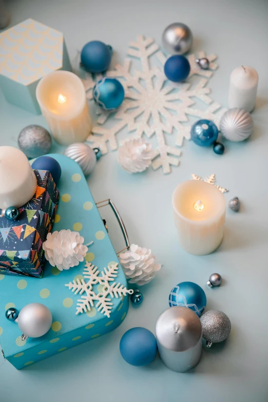 a blue gift box sitting on top of a table, a still life, trending on pexels, white candles, with lots of thin ornaments, ilustration, square