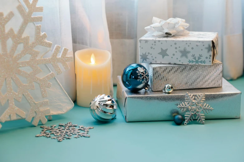 a pile of presents sitting on top of a table next to a candle, light and space, blue and silver, silver，ivory