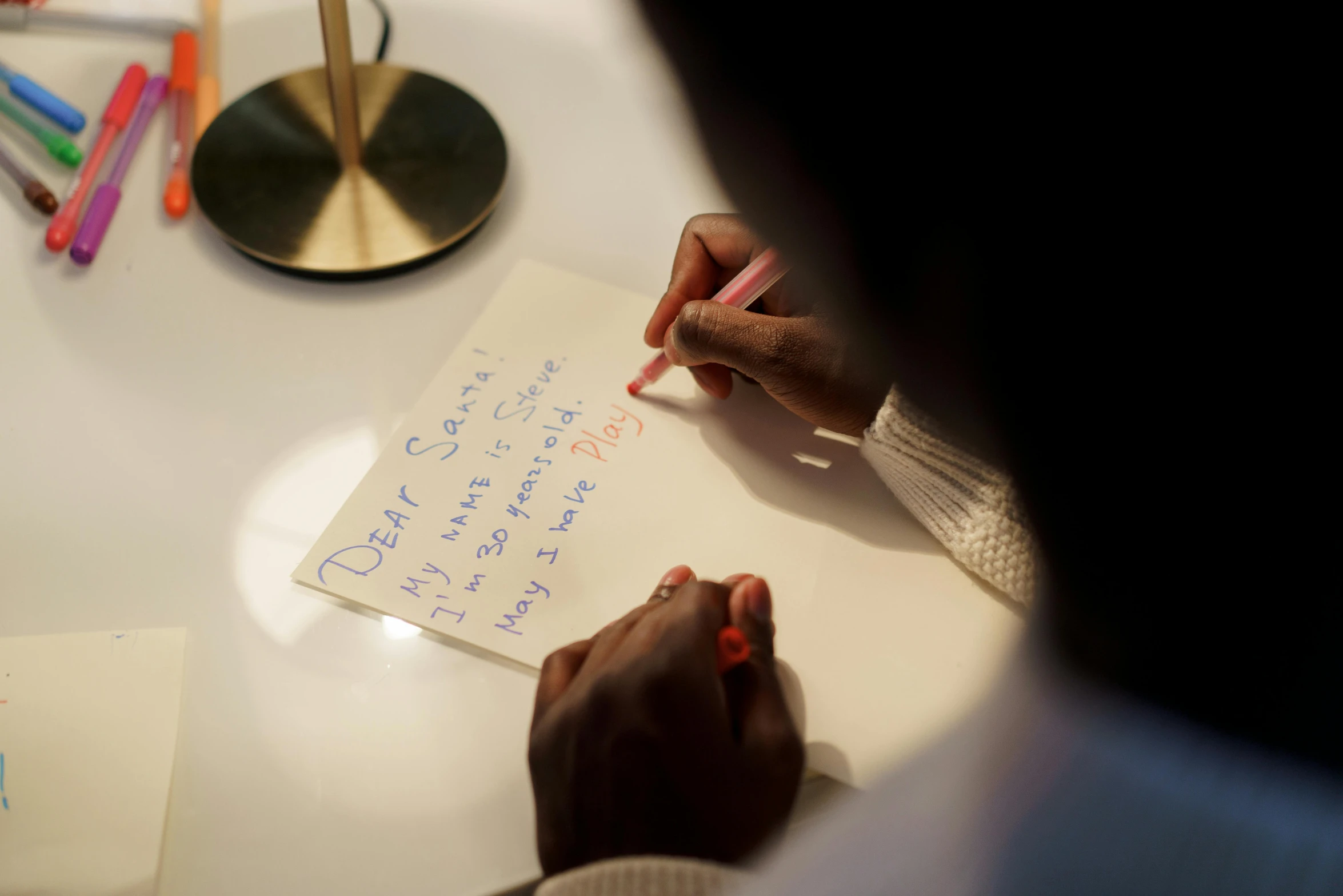 a person sitting at a table writing on a piece of paper, adut akech, holiday season, bottom angle, ignant