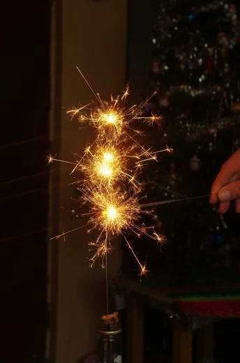 a person holding a sparkler in front of a christmas tree, a stipple, by David Simpson, pexels, on a candle holder, long spikes, vertical orientation, insanly detailed