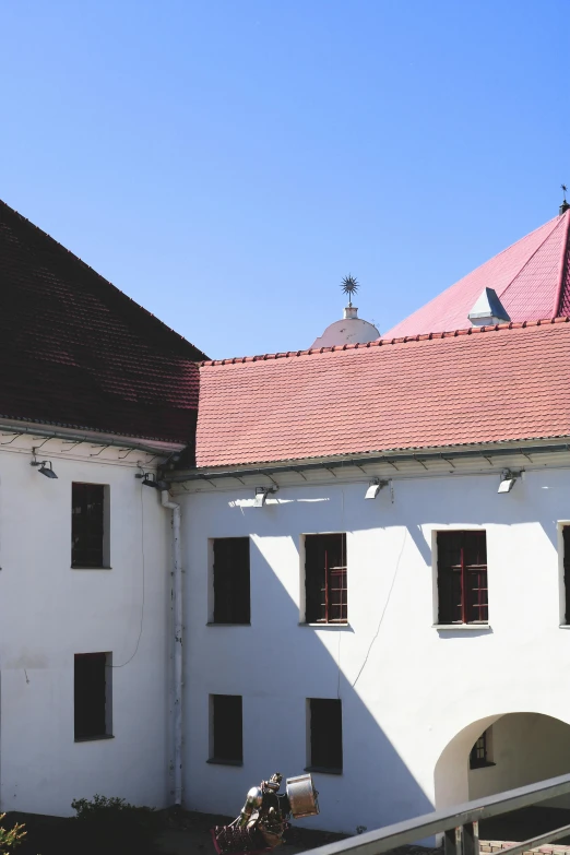 a large white building with a red roof, a photo, inspired by Gyula Aggházy, in a monestry natural lighting, rooftop, square, museum