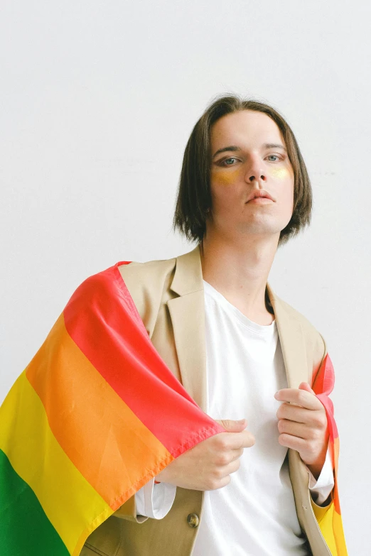 a man in a suit holding a rainbow flag, an album cover, by Jessie Alexandra Dick, androgynous face, wearing a brown cape, looking off to the side, julian ope