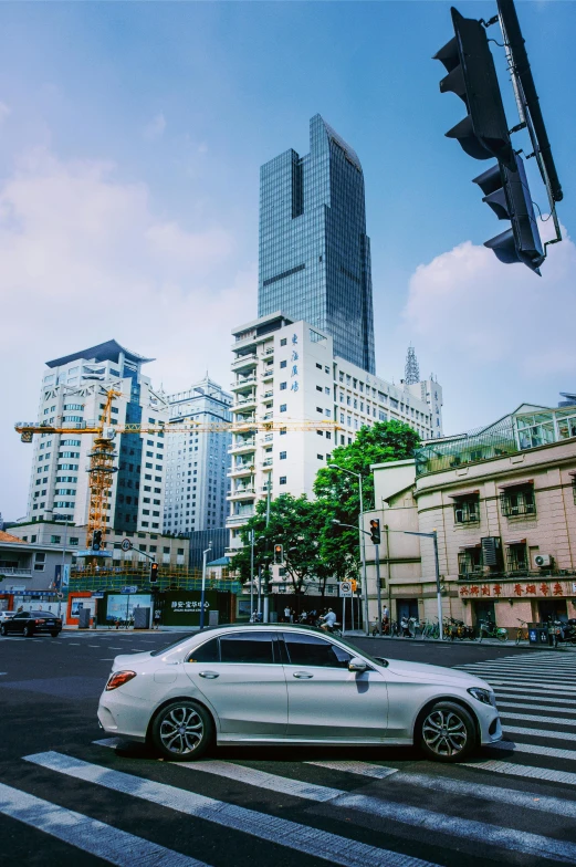 a white car driving down a street next to tall buildings, hou china, square, high quality picture, streetscapes