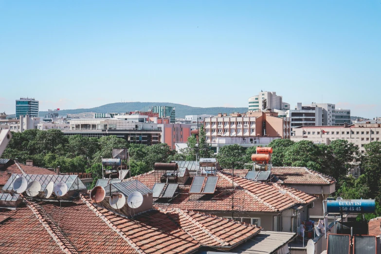 a view of a city from the top of a building, by Emma Andijewska, orange roof, jovana rikalo, clear blue skies, satellite dishes