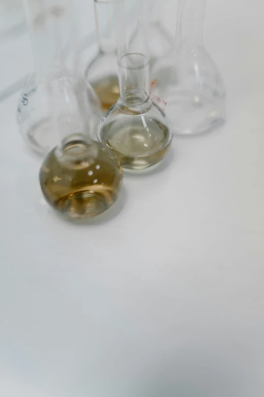 a group of wine glasses sitting on top of a table, chemicals, on a white table, f 2. 8 3 5 mm, cysts