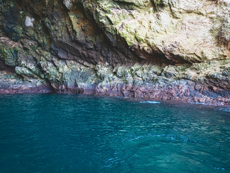 a close up of a body of water near a cliff, picton blue, inside the wishing well cavern, brown, calm seas