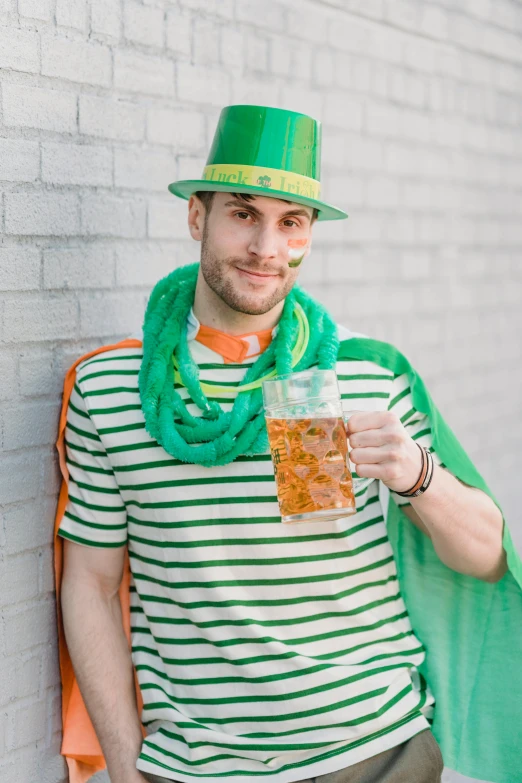 a man in a green hat holding a glass of beer, inspired by Mór Than, stripes, holy themed, trending photo, college