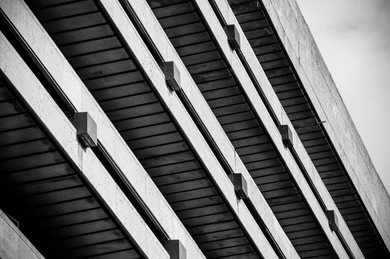 a black and white photo of a building, a black and white photo, inspired by Ned M. Seidler, unsplash, brutalism, hdr detail, square lines, balconies, under bridge