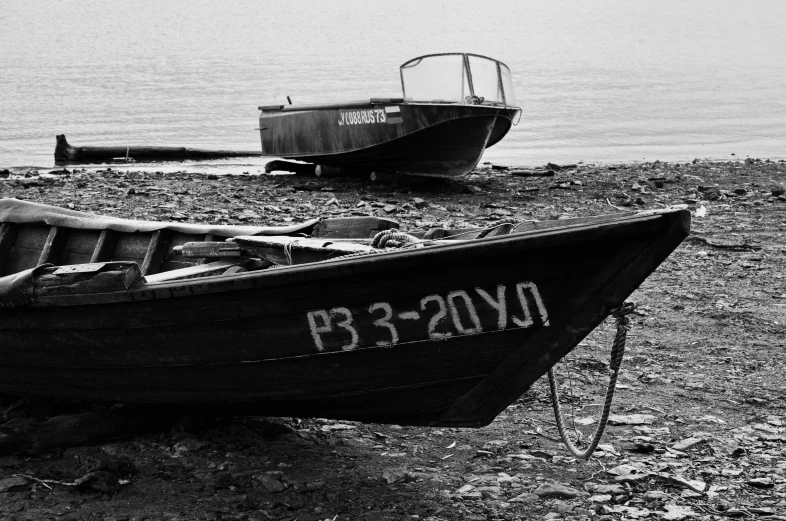 a couple of boats sitting on top of a beach, a black and white photo, by Alexander Deyneka, pixabay, soviet yard, a close-up, hunting, black sand