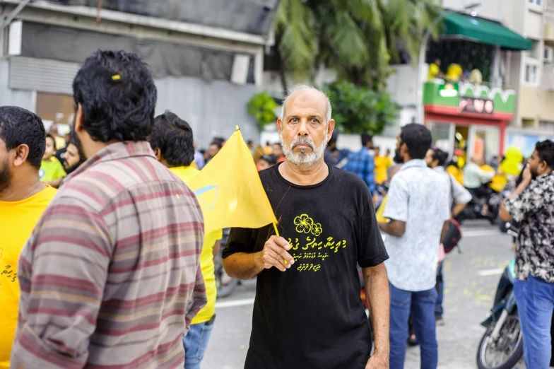 a man in a black shirt holding a yellow flag, hurufiyya, candid photography, avatar image