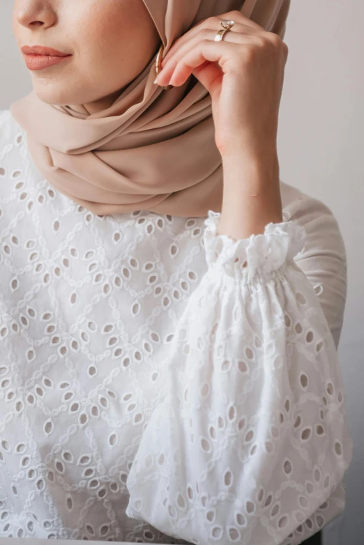 a woman wearing a hijab sitting at a table, inspired by Maryam Hashemi, trending on pexels, arabesque, white puffy outfit, detail texture, touching her clothes, wearing a light shirt