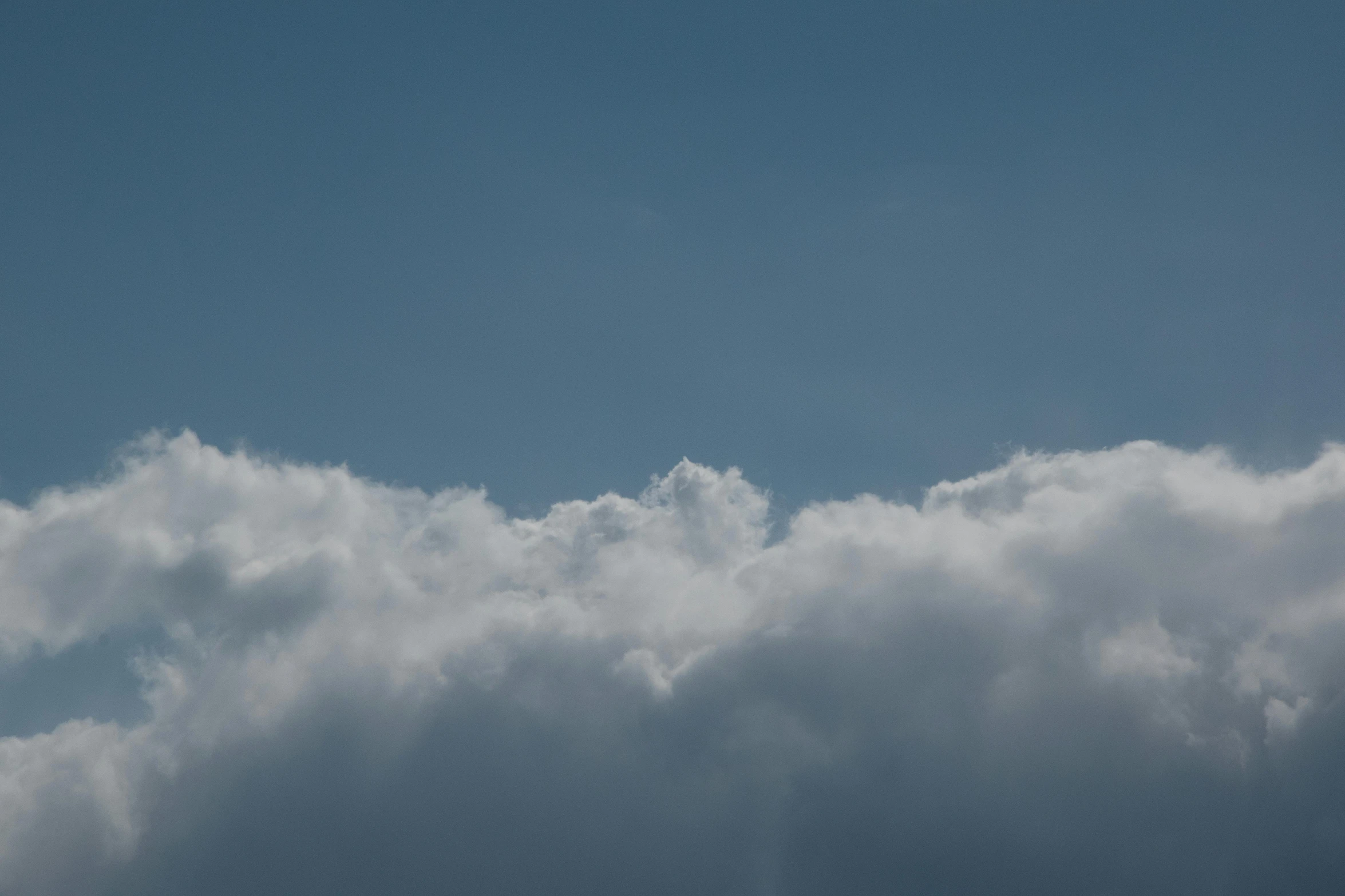 a plane flying through a cloudy blue sky, by Peter Churcher, unsplash, sitting in a fluffy cloud, seen from a distance, cloudless-crear-sky, giant cumulonimbus cloud