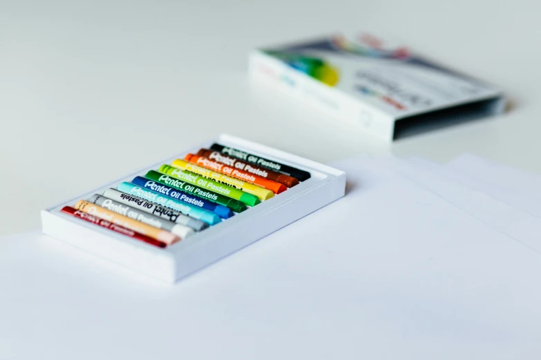 a box of crayons sitting on top of a table, professional product shot, multi colour, helvetica, oil pastel