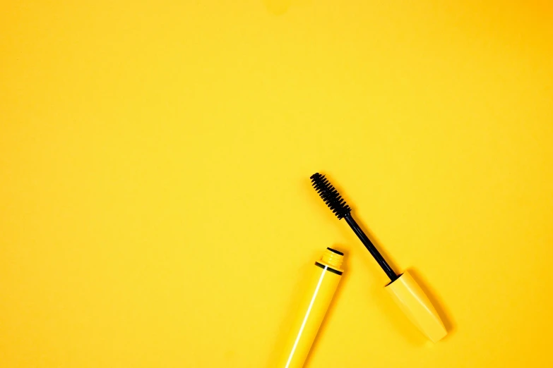 two mascara brushes next to each other on a yellow background, by Carey Morris, pexels contest winner, minimalism, black lipstick, 🦩🪐🐞👩🏻🦳, an eye, on a canva