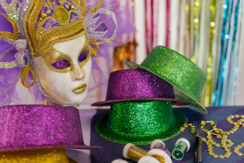 a couple of hats sitting on top of a table, inspired by Mardi Barrie, trending on pexels, renaissance, glitter makeup, green and purple, parade floats, finely masked