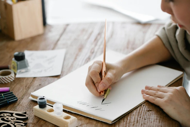 a woman sitting at a table writing on a piece of paper, trending on pexels, visual art, estrange calligraphy, painting on a canvas, uppercase letter, handcrafted