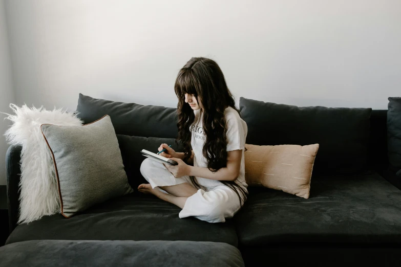 a woman sitting on a couch reading a book, by Carey Morris, pexels contest winner, happening, playing games, avatar image, teenager girl, instagram post