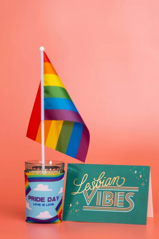 a cup of coffee with a rainbow flag next to it, a portrait, happening, jar on a shelf, official store photo, candles!, really good vibes