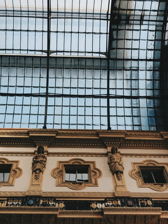 a clock mounted to the side of a building, an album cover, inspired by Thomas Struth, unsplash contest winner, neoclassicism, large glass ceilings, wes anderson style, archways between stalagtites, trending on vsco