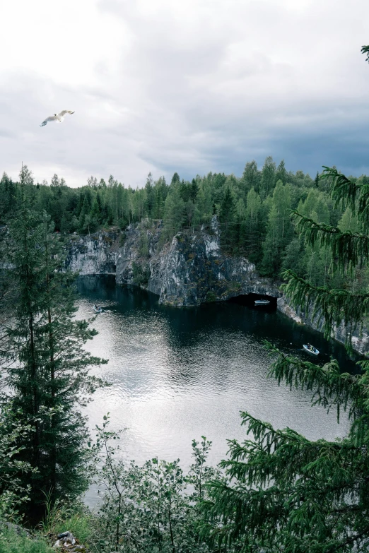 a large body of water surrounded by trees, an album cover, inspired by Eero Järnefelt, pexels contest winner, hurufiyya, rock quarry location, tarmo juhola, grey, cave