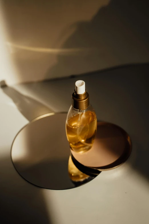 a bottle of liquid sitting on top of a table, shades of gold display naturally, skincare, product image, designer product
