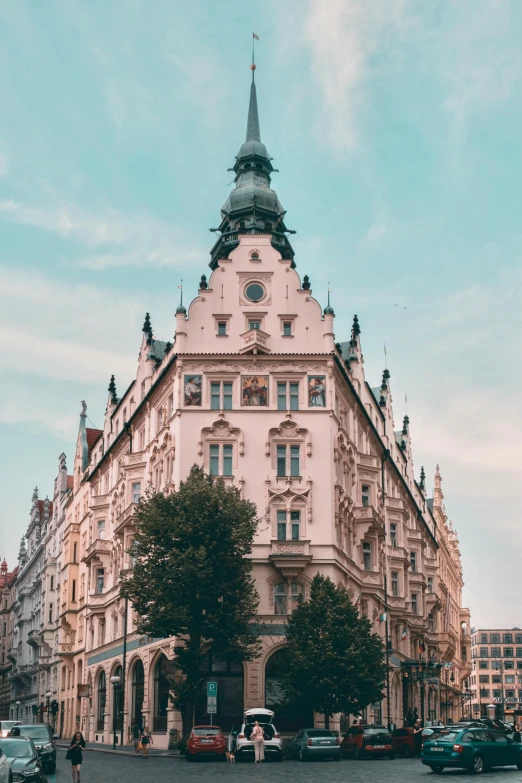 a tall building sitting on the side of a road, inspired by Mihály Munkácsy, pexels contest winner, art nouveau, rounded roof, prague, pastel hues, symmetrical crown