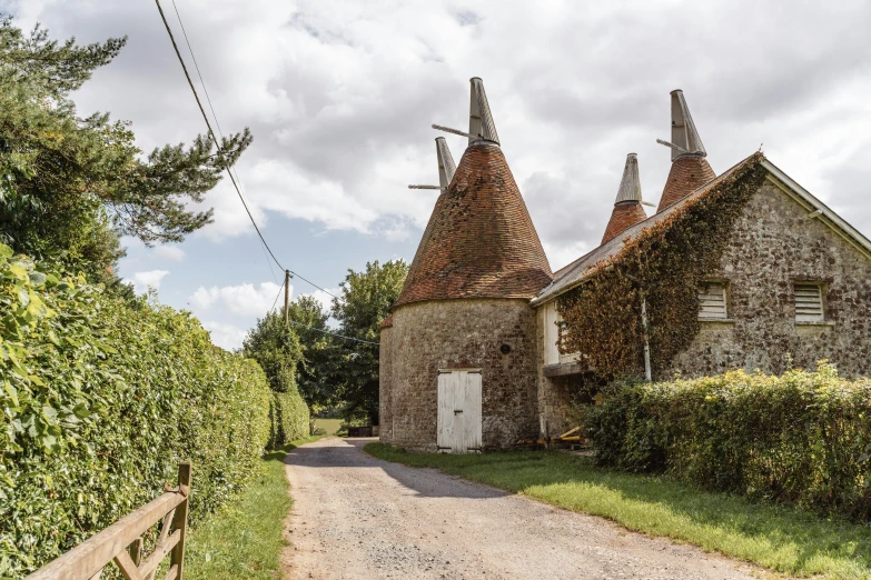a stone building sitting next to a dirt road, inspired by Pierre Toutain-Dorbec, pexels contest winner, renaissance, pointy conical hat, cottages, gilleard james, madgwick