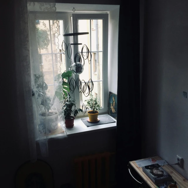 a table in front of a window with a potted plant on it, a picture, post - soviet courtyard, snapchat photo, no lights in bedroom, album photo