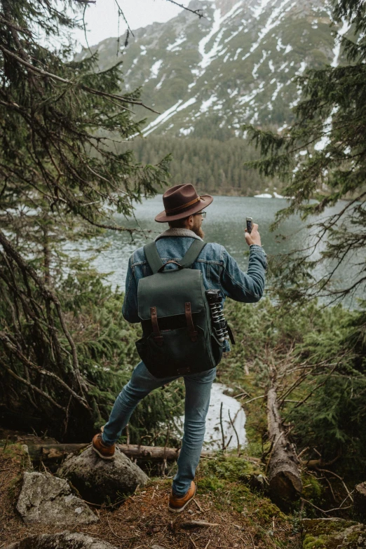 a man taking a picture of a mountain lake, by Sebastian Spreng, walking through the trees, carrying a saddle bag, stylish pose, minn