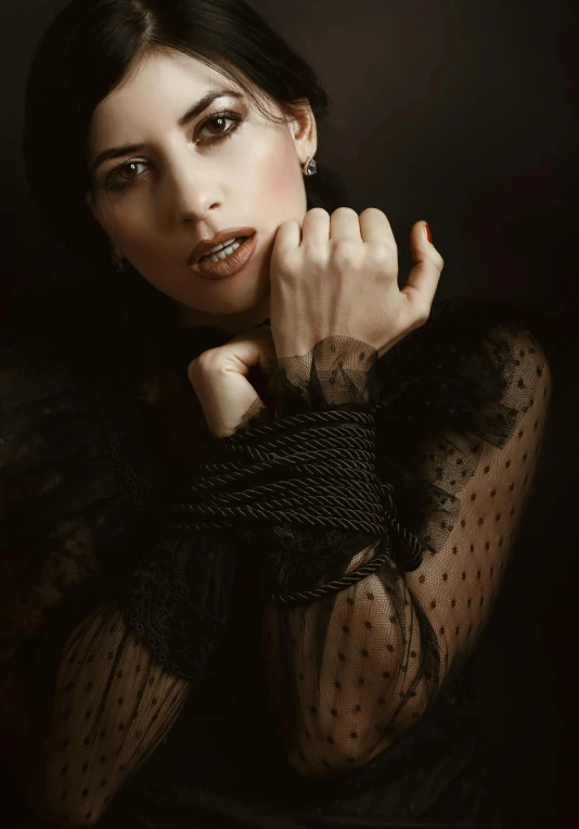 a woman in a black dress posing for a picture, an album cover, inspired by Artemisia Gentileschi, pexels contest winner, rope, medium format. soft light, jewelry photography, dressed in a lacy