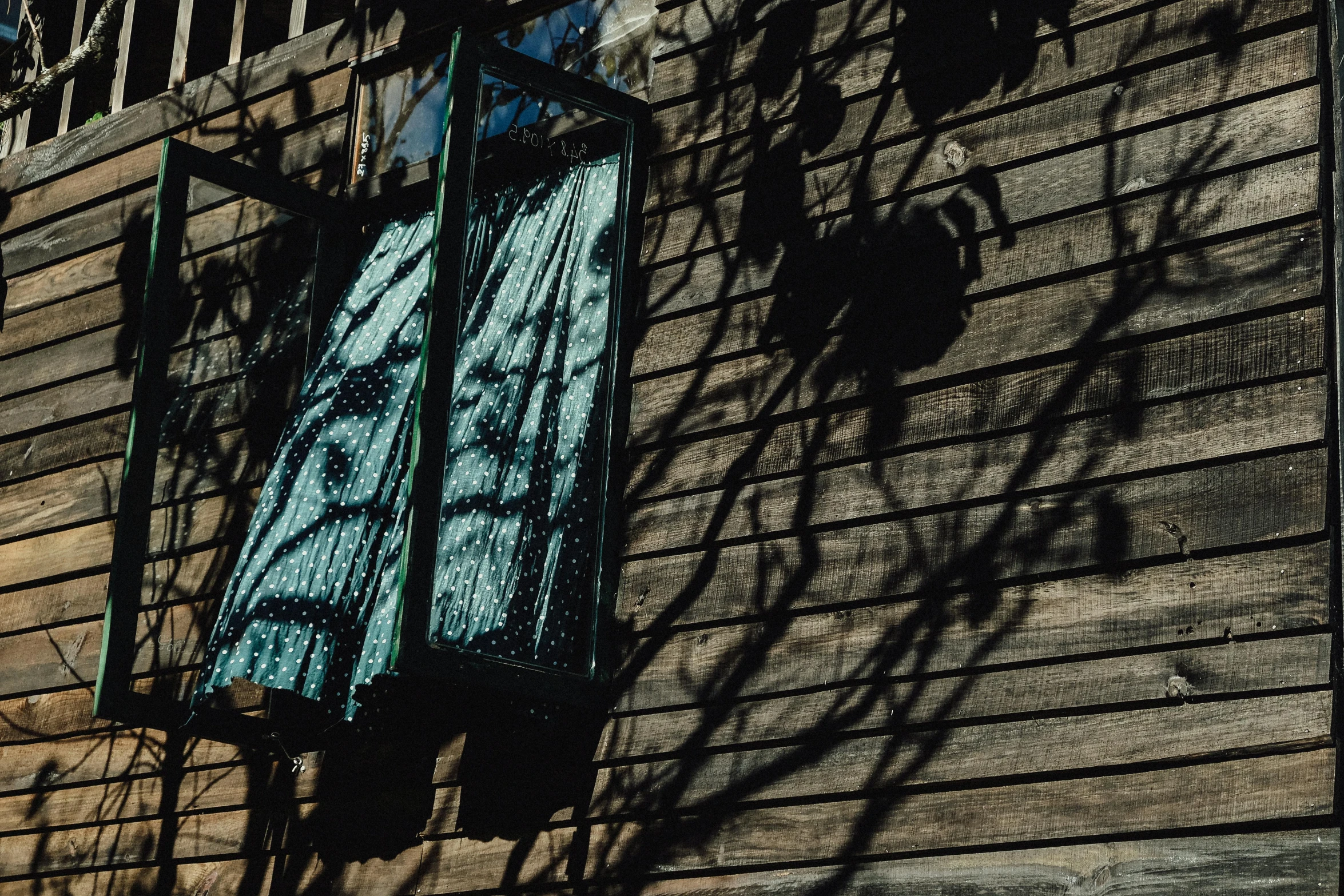 a window that is on the side of a building, inspired by Elsa Bleda, unsplash, shadows from trees, lantern, wooden cottage, 2 0 0 0's photo