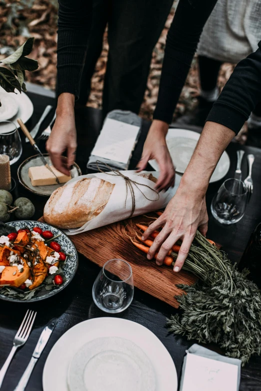 a group of people standing around a table with food, during autumn, hand holding a knife, profile image, feature