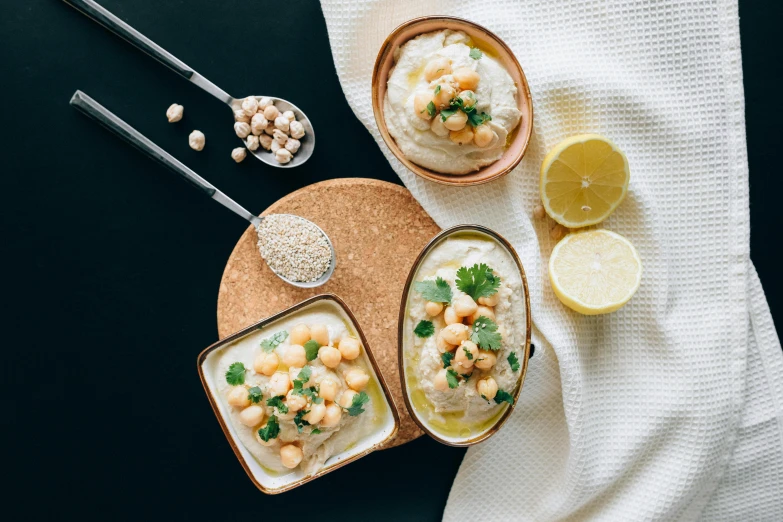 a couple of bowls filled with food on top of a table, by Emma Andijewska, trending on unsplash, dau-al-set, humus, background image, recipe, middle eastern skin