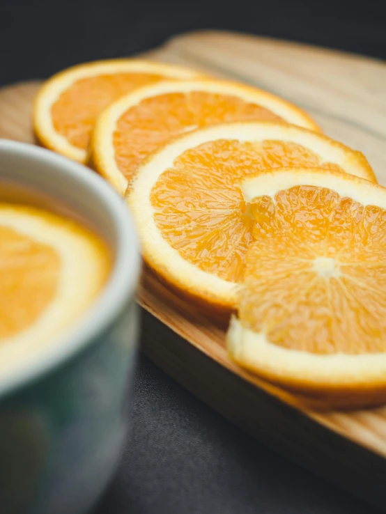 sliced oranges on a cutting board next to a cup of coffee, by Anna Haifisch, trending on unsplash, is ((drinking a cup of tea)), bottom body close up, multiple stories, half turned around