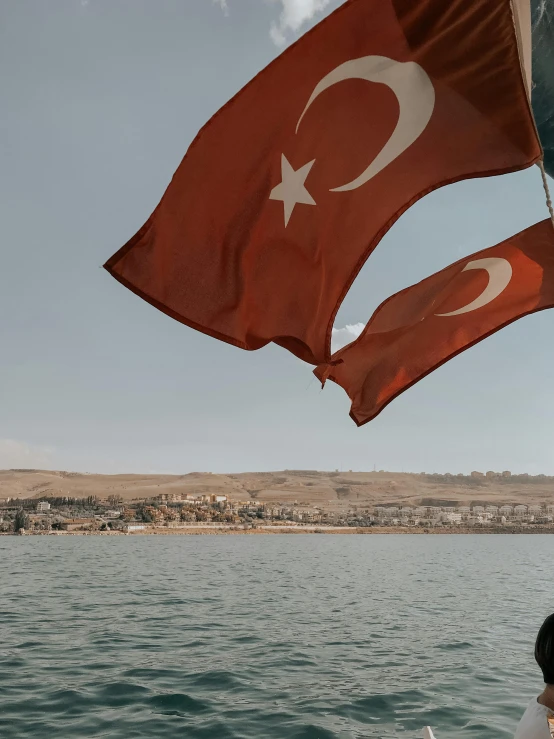 a couple of people that are on a boat, a colorized photo, by Ismail Acar, pexels contest winner, hurufiyya, flag, pov photo, background image, turkey