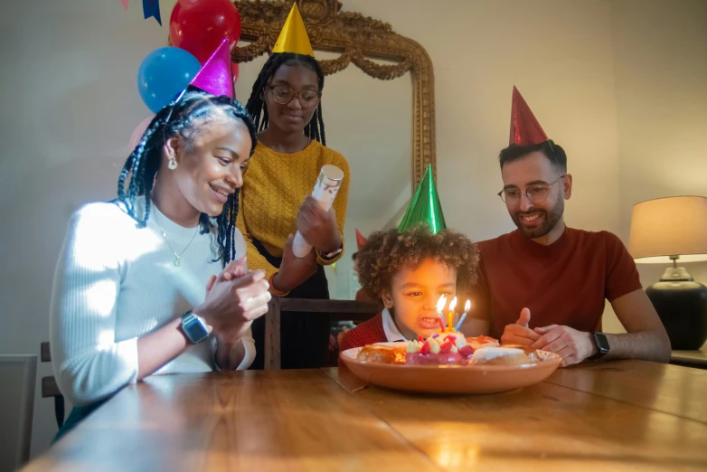 a family celebrating a birthday with a cake, a portrait, by Sam Dillemans, pexels, figuration libre, photo of a black woman, wearing a party hat, tabletop gaming, holding a candle holder