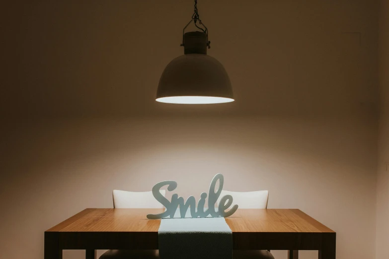 a dining room table with a smile sign on it, trending on pexels, ambient teal light, modern studio light soft colour, somber lighting, sitting at table