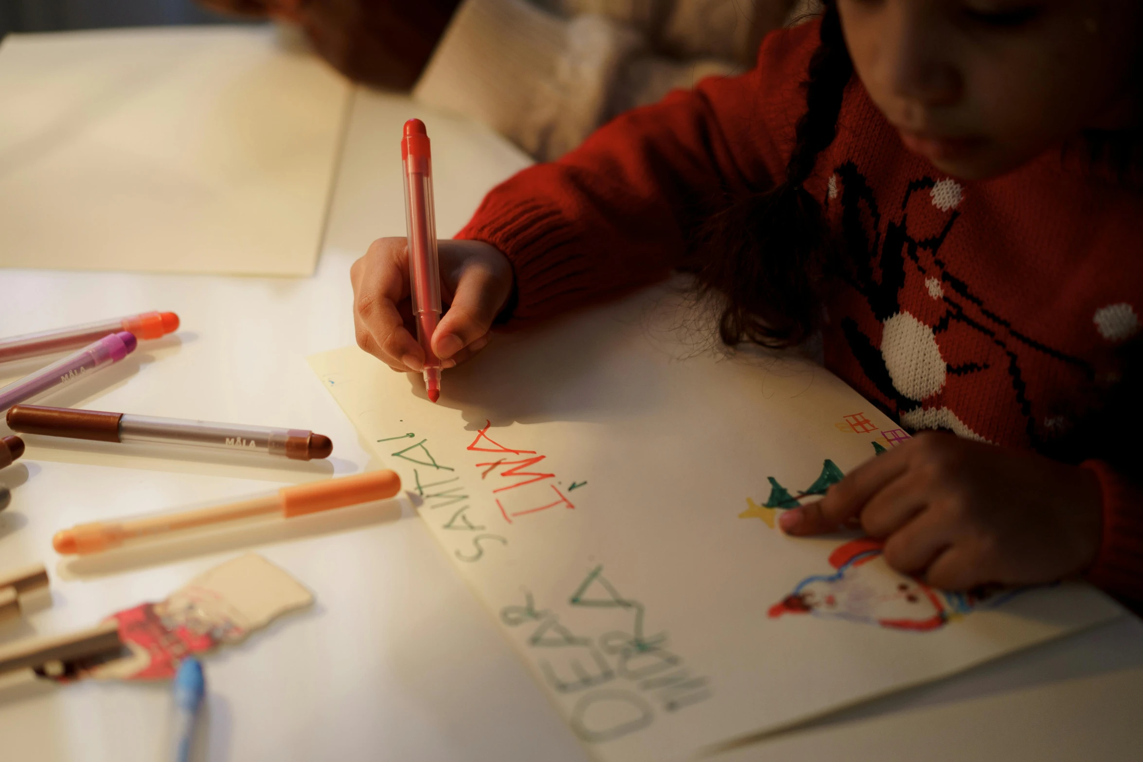 a little girl is drawing on a piece of paper, a child's drawing, by Emma Andijewska, pexels contest winner, santa's workshop, back towards camera, riyahd cassiem, eva elfie