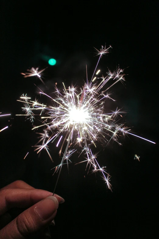 a person holding a sparkler in their hand, in 2 0 1 5, magnesium, starburst, shiny silver