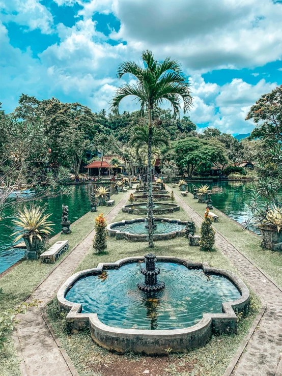 a fountain in the middle of a lush green park, by Daniel Lieske, pexels contest winner, next to a tropical pool, mystical lake view vista, 💋 💄 👠 👗, water temple