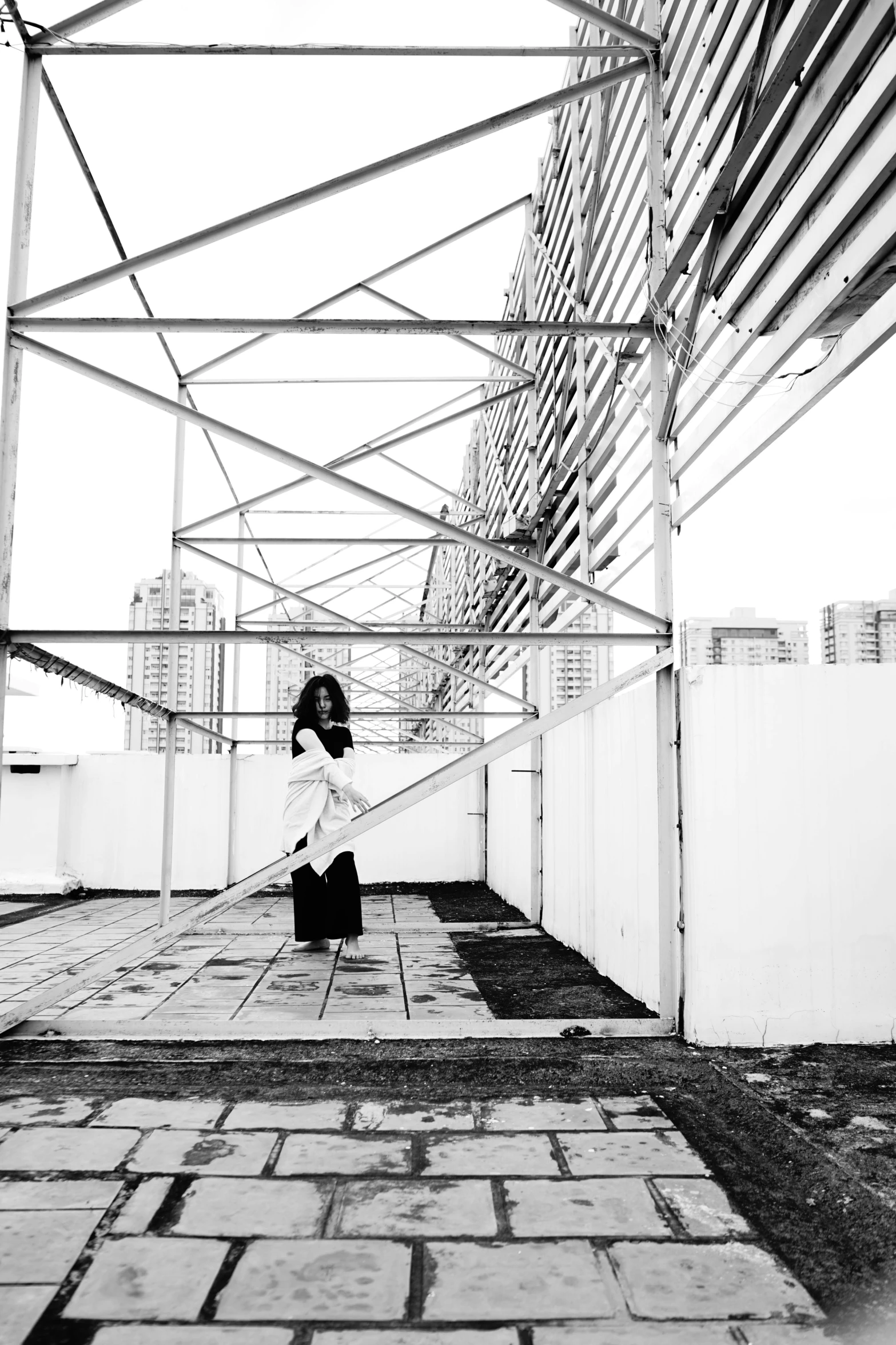 a black and white photo of a woman walking down a walkway, inspired by Cheng Jiasui, conceptual art, rooftop party, ameera al-taweel, low quality photo, square